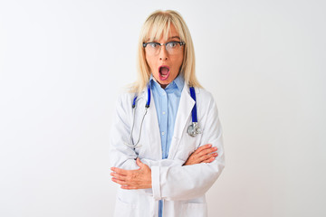Middle age doctor woman wearing glasses and stethoscope over isolated white background afraid and shocked with surprise expression, fear and excited face.