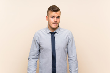 Young blonde businessman over isolated background having doubts and with confuse face expression