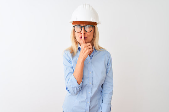Middle age architect woman wearing glasses and helmet over isolated white background asking to be quiet with finger on lips. Silence and secret concept.