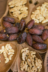 dried dates and walnuts on a wooden dish. vertical photo of oriental sweets.