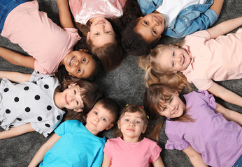 Adorable little children lying on floor together indoors, top view. Kindergarten playtime activities