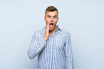 Young handsome blonde man over isolated blue background with surprise and shocked facial expression