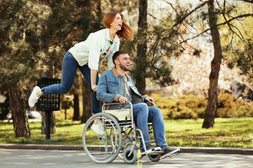 Young man in wheelchair and joyful woman at park