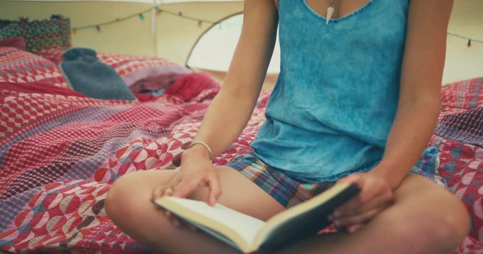 Young woman reading a book in big glamping tent