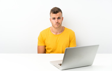 Young blonde man in a table with a laptop sad