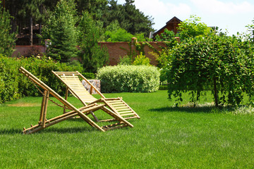 Wooden deck chairs in garden on sunny day