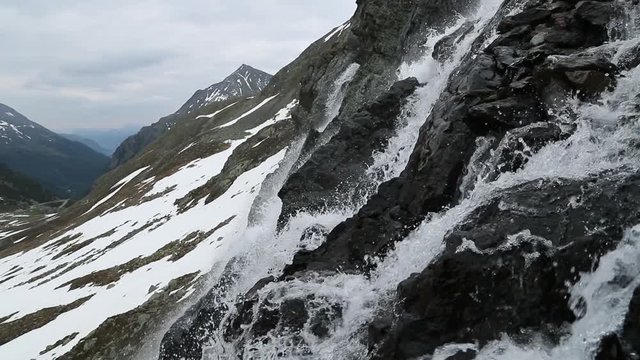 Beautiful waterfal near the Susch pass near Davos in Swizerland surrounded by snow and ice. Filmed in slowmotion in June.