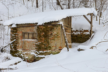 Old abandoned brick hut in a snowy winter forest
