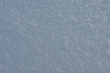 Blue snowdrift surface with shiny snowflakes on a winter evening
