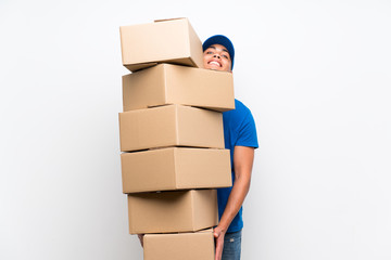 Delivery man over isolated white wall with lots of boxes