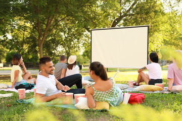 Young people with popcorn watching movie in open air cinema. Space for text