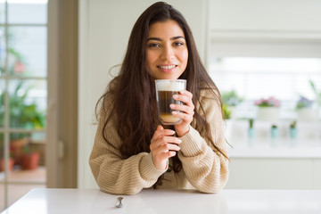 Beautiful young girl drinking a cup of coffee at home and smiling