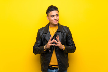 Young man over isolated yellow background scheming something