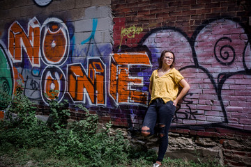 Obraz na płótnie Canvas teenage girl leaning against brick wall of graffiti