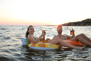 Obraz premium Happy young couple on inflatable rings in water