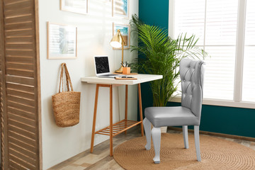 Fototapeta na wymiar Stylish home workplace with elegant grey chair near window. Interior design