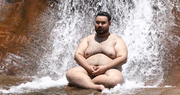 Fat people are refreshing with beautiful waterfalls, male tourists relax under the waterfall in the forest,