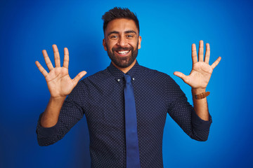 Young indian businessman wearing elegant shirt and tie standing over isolated blue background...
