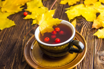 Yellow and orange fallen maple leaves on dark brown wood table background.