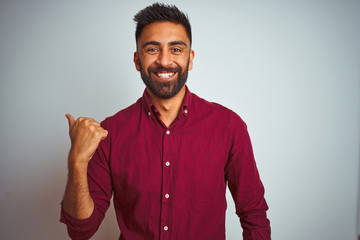 Young indian man wearing red elegant shirt standing over isolated grey background smiling with...