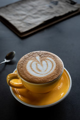 A cup of coffee with beautiful latte art and drink menu on black table background.