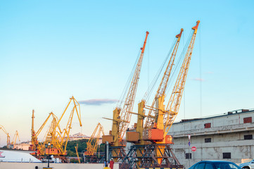 Fototapeta na wymiar Old port cargo cranes against the evening blue sky
