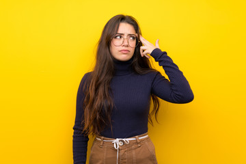 Teenager girl over isolated yellow wall with problems making suicide gesture