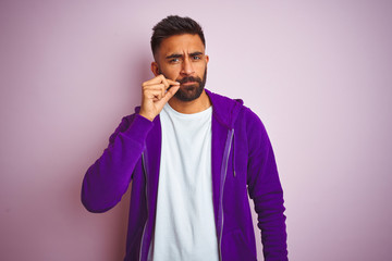 Young indian man wearing purple sweatshirt standing over isolated pink background mouth and lips...