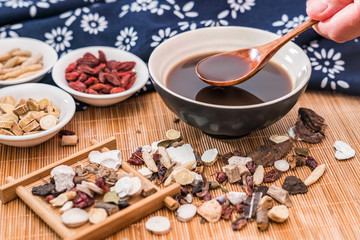 All kinds of traditional Chinese medicine and a bowl of traditional Chinese medicine soup scattered on the bamboo mat
