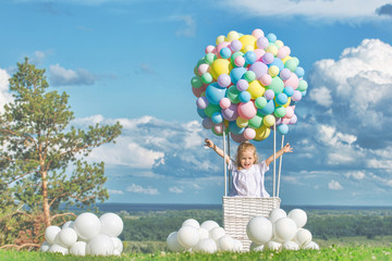 Little cute child girl beautiful and happy on green grass with balloon airship on blue sky background with clouds