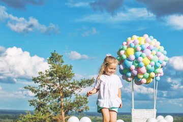 Little cute child girl beautiful and happy on green grass with balloon airship on blue sky background with clouds