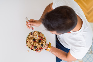 Above angle of handsome man eating healthy cereals for breakfast in the morning