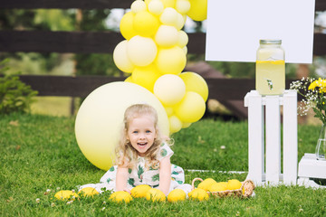 Little cute child girl beautiful and happy on green grass with balloons and lemonade