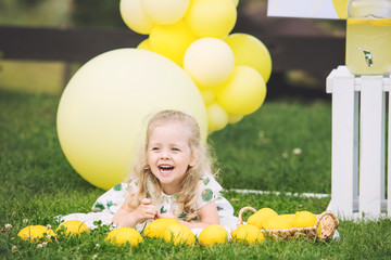 Little cute child girl beautiful and happy on green grass with balloons and lemonade