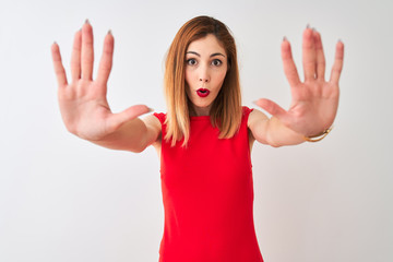 Redhead businesswoman wearing elegant red dress standing over isolated white background doing stop gesture with hands palms, angry and frustration expression