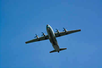 Fototapeta na wymiar gray military plane flies in the blue sky Peaceful flight demonstration. Memory. Day of the city.. Air show