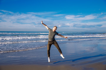 Guy on ocean beach jumped air with his arms outstretched in both directions