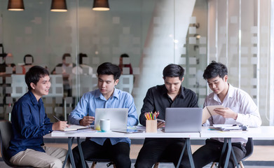 Team collaboration meeting start up. Group of young Asian men who using laptop computer to discuss and talking at office.
