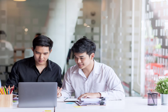 Two young asian businessman using laptop working at office on new project.