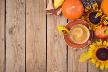Autumn concept with coffee cup, pumpkin, apples and sunflowers on wooden table. Thanksgiving holiday background. Top view from above