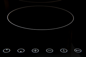 A Modern induction cooker with control buttons. The electric hob closeup. Stove top panel at modern kitchen. Kitchen Electric hob with ceramic surface and touch control panel.