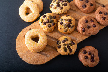 Food concept assortment of homemade sugar butter cookies on wooden board on black slate stone plate with copy space