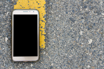 A Smart phone with black screen on the background of the yellow road line with copy space.