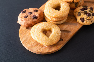 Food concept assortment of homemade sugar butter cookies on wooden board on black slate stone plate with copy space