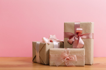 set of beautiful different gift boxes made by handmade with pink bows on a wooden table with a pink background. flat lay