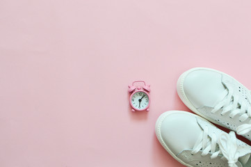 Fototapeta na wymiar White sneakers on a pink background in a pink watch. The concept of sports, training. Losing weight and sport concept. Flat lay.Copyspace for text.