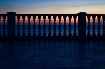 Fence of balusters against the sunset and the sea