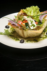 Classic Greek salad with feta cheese, tomato, cucumber, onion and olives. Exquisite dish. Creative restaurant meal concept. Haute couture food on black. Fine dining concept.