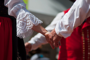 Closeup of hands of dancers with alsatian costume in the street - obrazy, fototapety, plakaty