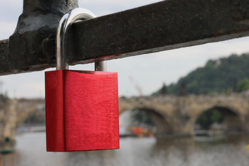 Hanging red padlock, in the background, Charles Bridge in Prague.